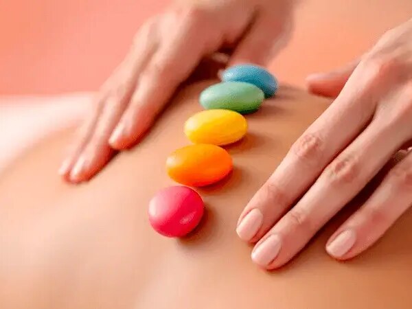 Massage des chakras avec Sophie Antille : pierres colorées alignées sur le dos pour équilibrer les chakras et harmoniser l’énergie