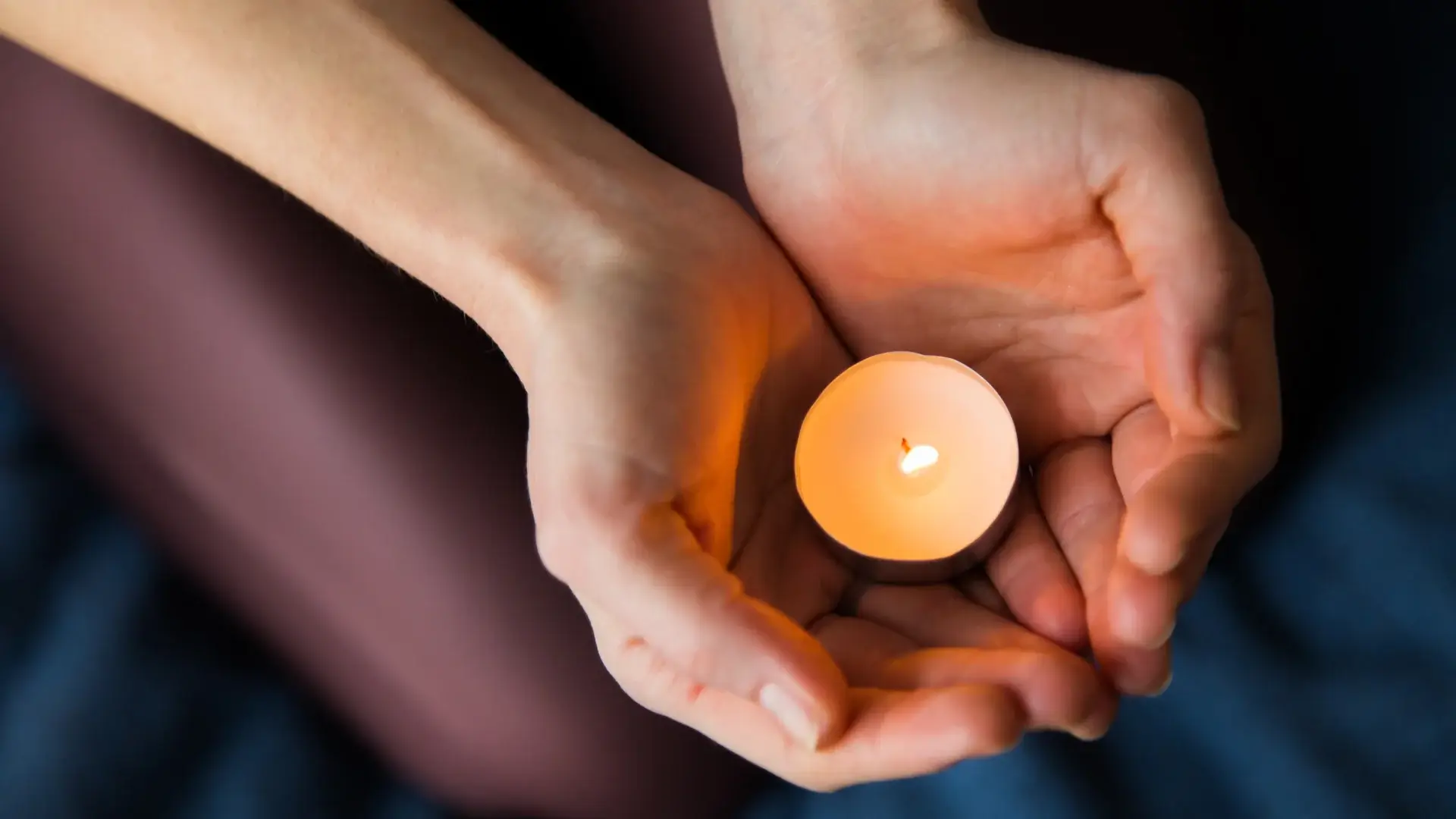 Mains tenant délicatement une bougie allumée, symbolisant la transmission de chaleur et l'apaisement du soin énergétique LaHoChi.