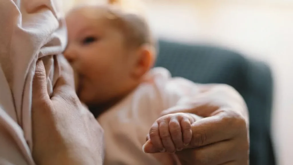 Bébé allaité tenant la main de sa mère illustrant le webinaire allaitement avec Sophie Antille