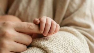 Bébé tenant le doigt de sa mère illustrant le langage silencieux des bébés avec Sophie Antille