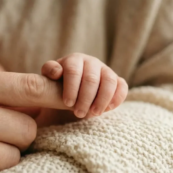 Bébé tenant le doigt de sa mère illustrant le langage silencieux des bébés avec Sophie Antille